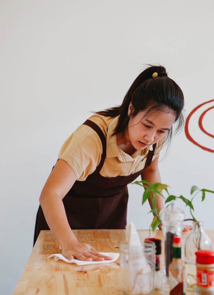 about-01 Asian woman wiping a wooden table in a restaurant, showcasing small business operations.