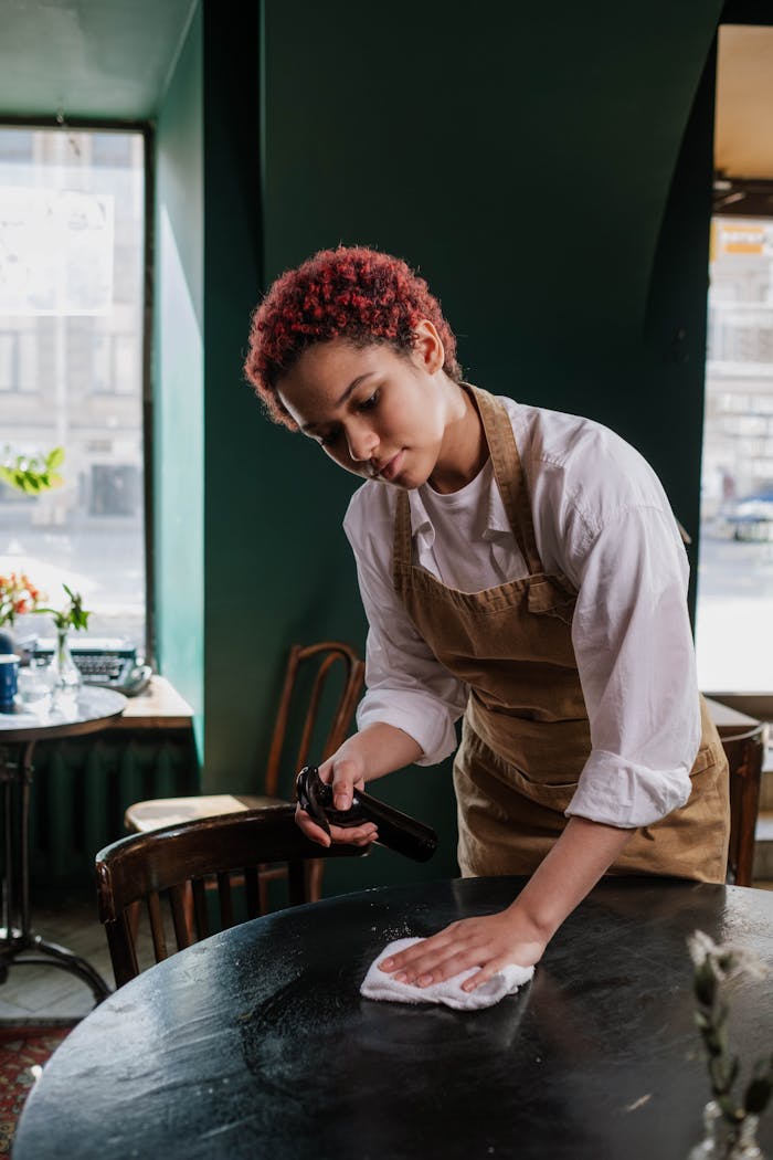 services-02 Young waitress cleans a table in a cozy café, capturing the essence of service and hospitality.